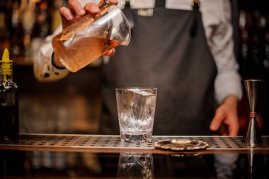 Profesyonel barmen pourring bir karıştırma üzerinden taze alkollü kokteyl içki cam çelik bar counter