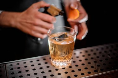 Profesyonel barmen bir portakal lezzet ve taze alkollü kokteyl içmek çubuğu ekleme atışa hazır sayaç