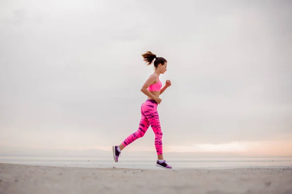 Mooie Jonge Vrouw Gekleed Roze Sportswear Lopen Het Strand Tijdens — Stockfoto