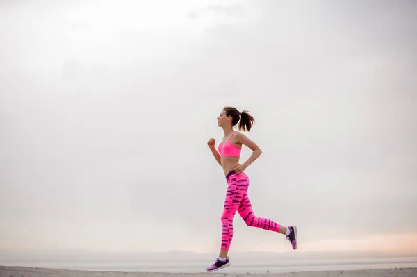 Jonge Mooie Vrouw Gekleed Roze Sportswear Lopen Langs Zeekust Tijdens — Stockfoto