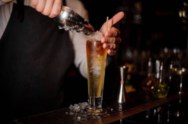Profesyonel barmen barda lezzetli yaz rum kokteyl ile cam içine buz ekleme sayaç