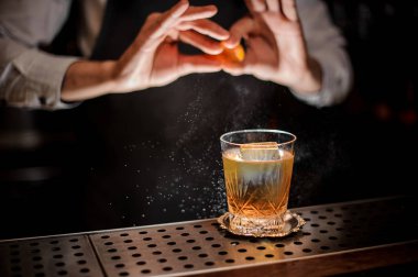 Profesyonel barmen suyu çubuğu'nda taze alkollü kokteyl içmek için bir portakal lezzet parçası ekleme sayaç