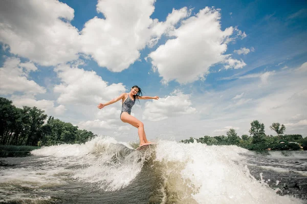 Genç güzel kadın güzel berrak gökyüzü arka plan üzerinde gölde wakeboard sürme
