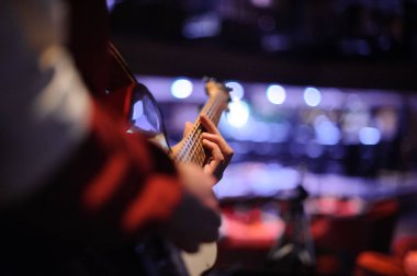 Gece kulübünde mavi ışıklar koyu arka plan üzerine onun elinde bir gitar ile ayakta adam
