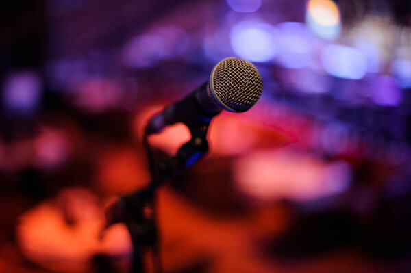 Microphone with metal body in holder on the blurred red and blue background in the night club