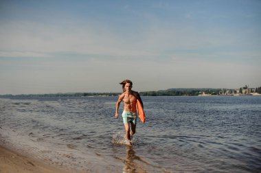 Nehir kıyısında yaz gününde hayat kurtaran ekipman ile birlikte çalışan yakışıklı seksi uzun saçlı plaj cankurtaran