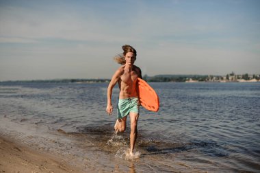 Nehir kıyısında yaz gününde hayat kurtaran ekipman ile birlikte çalışan aktif seksi uzun saçlı plaj cankurtaran