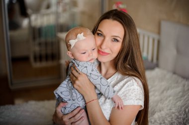 Arka plan bulanık üzerinde tatlı kendi odasında genç esmer anne küçük sarışın kızı tutan eller