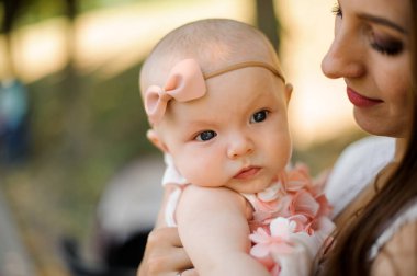 Genç esmer güzel anne küçük sarışın kızı genel parkta arka plan bulanık ellerinde tutan