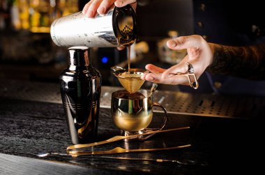 Bir alkollü kokteyl çelik shaker dan bakır fincan içine elek çubuğu üzerinden dökülen barmen sayaç