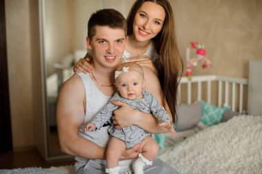 Kocası ve küçük kızları onların rahat odaları için hafif renklerde yatakta üzerinde arkasında duran kadın