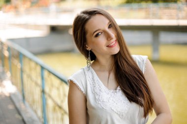 Muhteşem gülümseyen kadın zarif beyaz elbiseli genel park su birikintisi arka plan üzerinde duran siyah saçlı