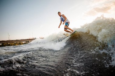 Nehir dalgalara karşı aşağı sürme aktif ve Genç wakesurfer açık gökyüzü üzerinde sıcak yaz günü