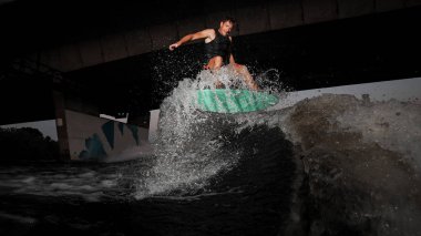 Nehir dalgalara karşı köprü aşağı yaz akşamları sürme aktif ve Genç wakesurfer