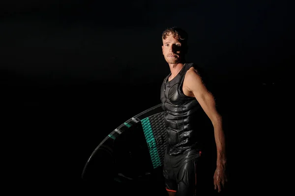 ハンサムな筋肉 Wakesurfer 黒と熱い夏の夜の暗い背景の上に立って — ストック写真
