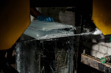 Adam özel bir araç ile büyük açık buz küp buz üretim tesisi karanlıkta kesim el ile yardım