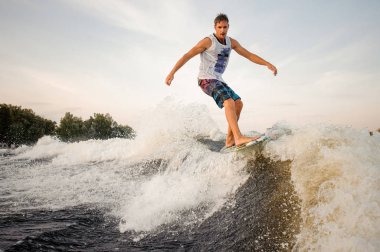 Arka planı panosunda nehir aşağı sürme etkin ve güçlü wakesurfer açık gökyüzü