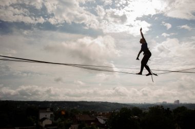 Açık mavi gökyüzü arka plan üzerinde slackline ip üzerinde yürüyen genç sarışın kadın