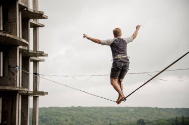 Yarım kalmış binaların ve berrak gökyüzü arka plan slackline ipe üzerinde yürüyen arka görünümü adam