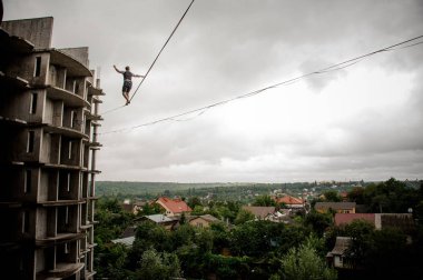 Arka görünümü adam arka plan ağaç ve berrak gökyüzü arasında evlerin slackline ip basamakta yapma