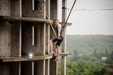 Yan görünümü genç slackline ip yarım kalmış binaların zemin üzerine oturan adam ve gökyüzü temizleyin