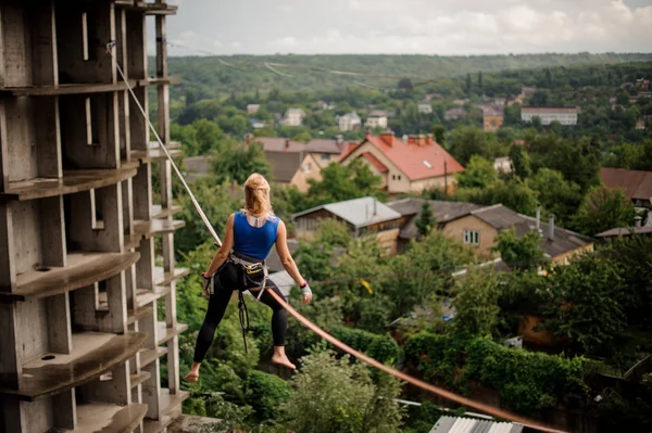 Rückansicht Blondine Sitzt Auf Dem Slackline Seil Zwischen Den Rohbauten — Stockfoto