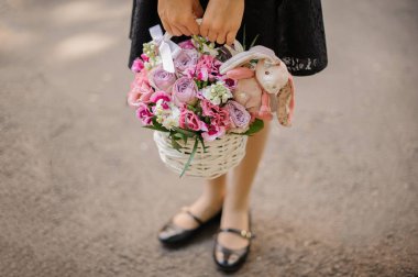 Liseli kız şirin bir sepet parlak pembe çiçekler tam tutan bir oyuncak tavşan ile dekore edilmiştir.