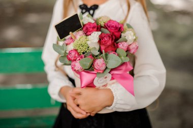 Bir bankta oturan ve bir kutu gül tutan küçük kız