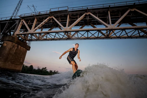 Спортсмен Молодий Чоловік Стрибає Пробудження Вниз Річці Хвилі Проти Мосту — стокове фото