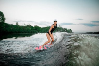Genç çekici esmer kadın portakal wakesurf Motorbot bulanık arka plan ağaç üzerinde yüksek dalga sürme