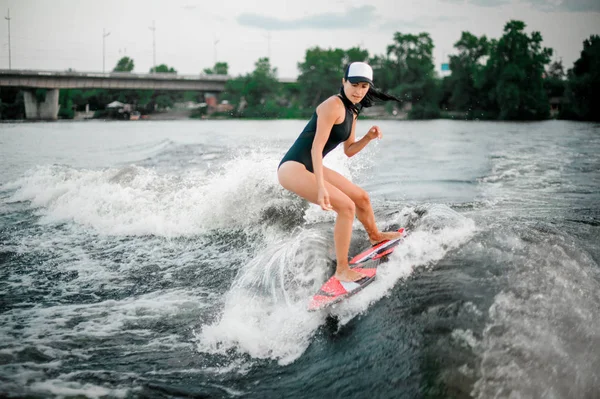 다리와 나무의 배경에 보트의 파도에 Wakesurf을 수영복에 — 스톡 사진