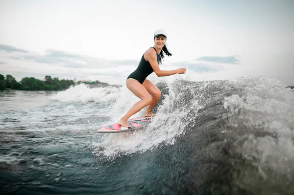 アクティブな女性の Wakesurf 木の背景にモーター ボートの高い波を曲げ膝の上に乗って — ストック写真