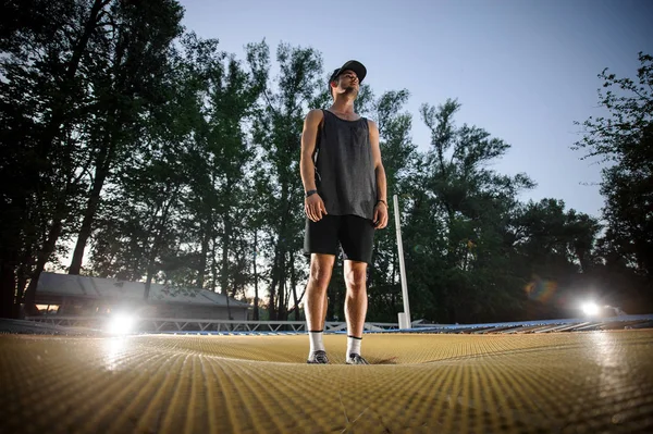 Junger Mann Mit Schirmmütze Der Abends Auf Dem Gelben Trampolin — Stockfoto