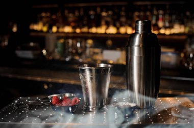 Profesyonel bar ekipmanları, shaker, cam ve çubuğu'nda düzenlenen maşa ile duman ışığında karşı karşı bar