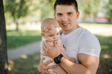 Mutlu gülümseyen genç baba ile şirin bebek kız parkta güneşli yaz gününde yürüyüş