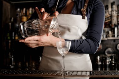 Kadın profesyonel barmen karanlık taze yaz içeceği zarif bir kokteyl cam içine dökme bar counter