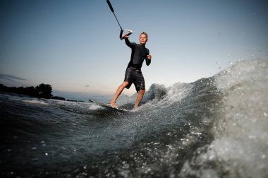 Sıçramalarına yaz akşam gökyüzü mavi nehir dalgalarla aşağı sürme mayo giymiş Wakesurfer