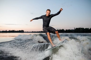 Genç wakesurfer bir uyku modundan çıkarma kurulu aşağı nehir dalgalara karşı mavi gökyüzü atlama