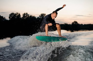 Genç wakesurfer Siyah mayo de akşam nehirden aşağı sürme bir uyku modundan çıkarma tahtada atlama