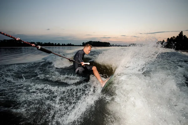Wakesurfer 穿着泳装骑在蓝色河波浪与飞溅在夏天晚上 — 图库照片