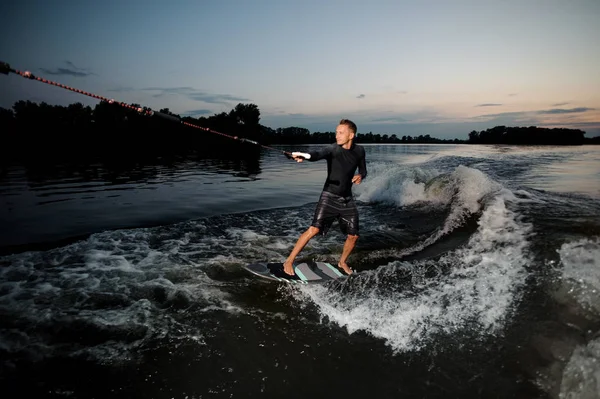 Wakesurfer 穿着泳装骑下蓝色河波浪与飞溅在夏天晚上 — 图库照片