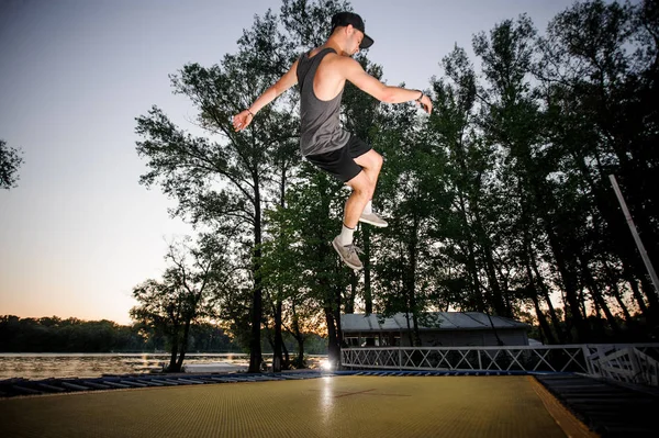 アクティブな若い男は 空の背景にある公園でカジュアルウェア ヌーディストトランポリンに身を包んだ — ストック写真