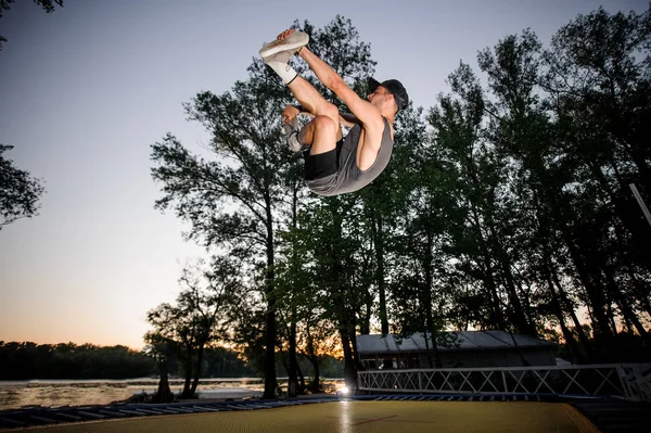 夕方の空の背景に公園でカジュアルウェア ヌーディストトランポリンに身を包んだ若い男 — ストック写真