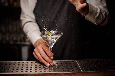 Barmen bir taze ve güçlü martini yaz kokteyl çubuğu'nda sıçrama yapma bir yeşil zeytin ile yapma