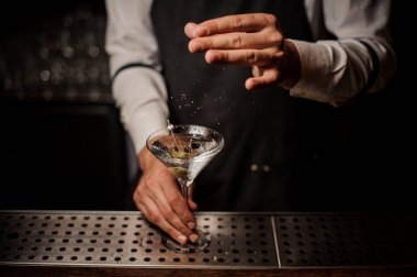 Barmen çubuğunda bir yeşil zeytin ile dekore edilmiş tuz güçlü bir martini kokteyl içine ekleme