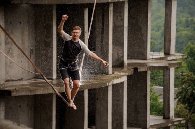 Etkin adam slackline yüksek boş yaz gününde binanın arka planı üzerinde dengeleme