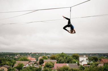 Yüksek bir slackline gri gökyüzü ve kent karşı yağmurlu yaz gününde Dengeleme ince sarışın kız
