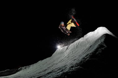 Freeride snowboard sıcak spor giyinmiş dreadlocks ile toz karda geceleri atlıyor