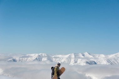 Gözlük, bir sırt çantası ve dağların fon karşı karda yürüme snowboard giyen adam yılında kayak ekipmanları,