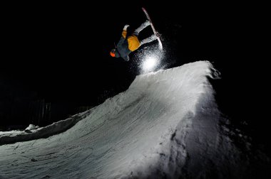 arka planı karanlık gökyüzü karlı kar fırtınası yükselterek Erkek atlet snowboard, atlama kayak kıyafeti
